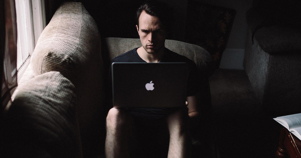 Man hiding to use his computer for cheating purposes.